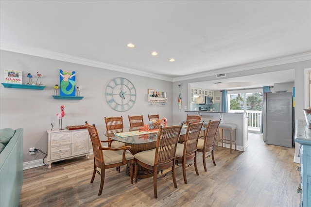 dining area with wood-type flooring and crown molding