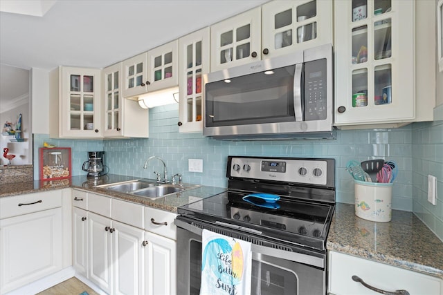 kitchen featuring white cabinetry, sink, tasteful backsplash, dark stone counters, and appliances with stainless steel finishes