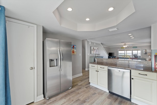 kitchen with a raised ceiling, ceiling fan, light wood-type flooring, white cabinetry, and stainless steel appliances