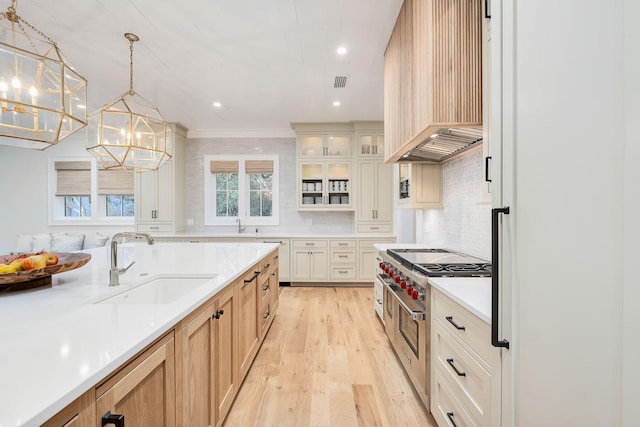 kitchen featuring light wood finished floors, a sink, double oven range, light countertops, and premium range hood