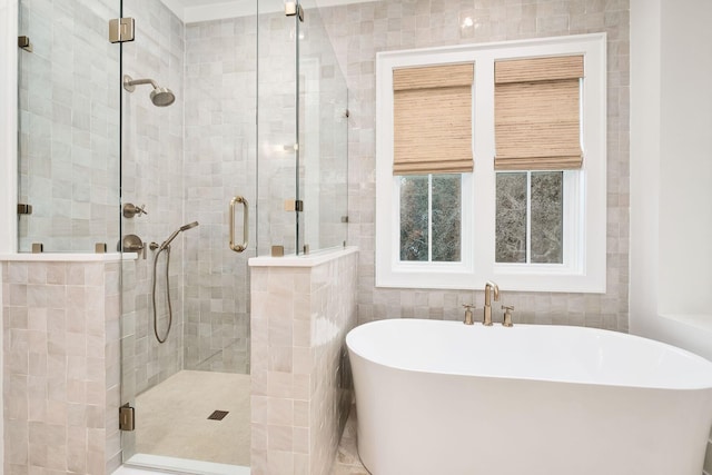 bathroom featuring tile walls, a stall shower, and a freestanding tub