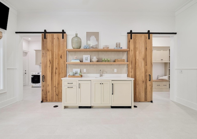 bar with a sink, crown molding, a barn door, and washer / dryer