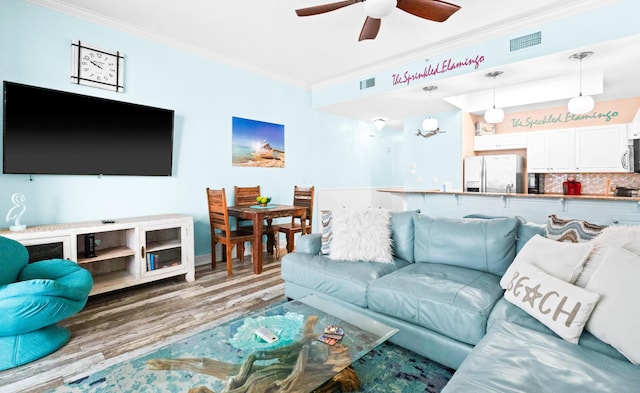 living room with crown molding, hardwood / wood-style floors, and ceiling fan