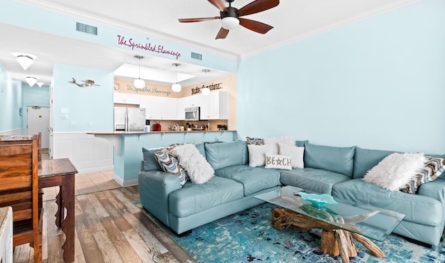 living room featuring ceiling fan, ornamental molding, and light wood-type flooring