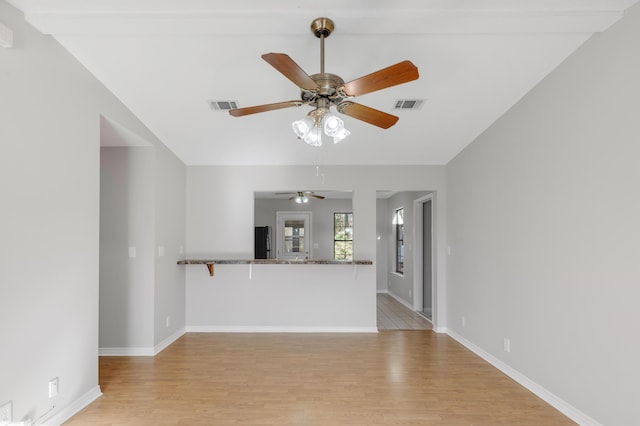 unfurnished living room featuring beam ceiling, ceiling fan, and light hardwood / wood-style flooring