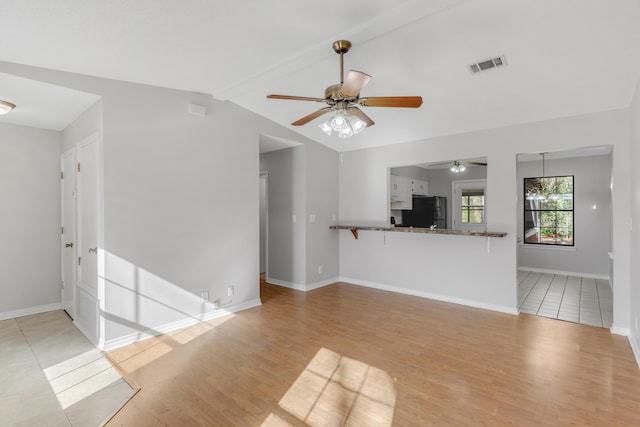 unfurnished living room featuring lofted ceiling with beams, light hardwood / wood-style flooring, and ceiling fan