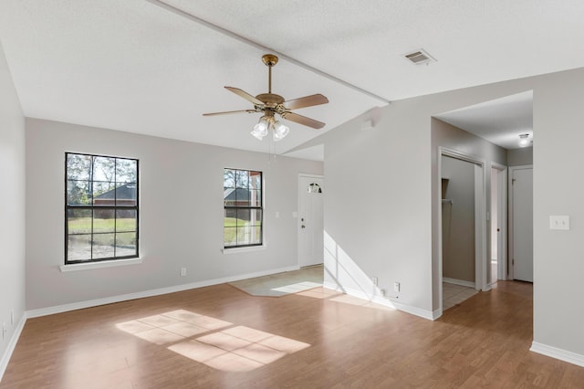 unfurnished room featuring ceiling fan, light wood-type flooring, lofted ceiling, and a textured ceiling