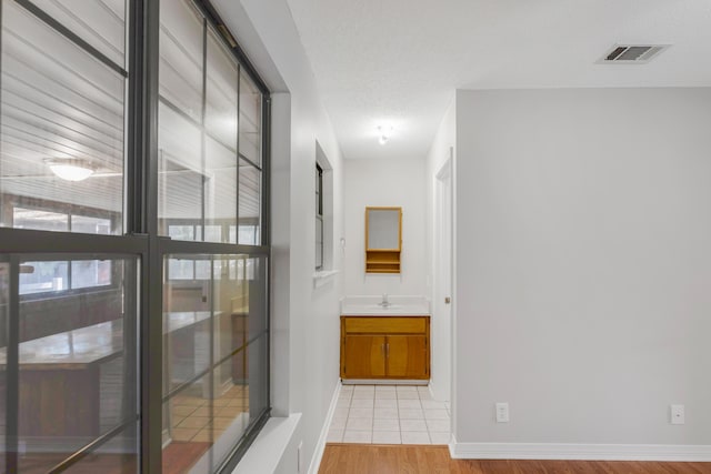 hallway featuring a textured ceiling, light hardwood / wood-style flooring, and sink