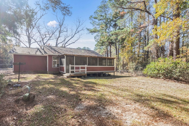 rear view of property with a lawn and a sunroom