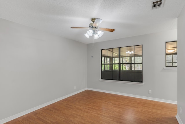 unfurnished room with a textured ceiling, light wood-type flooring, and ceiling fan