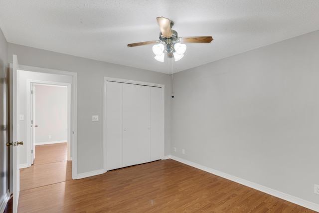 unfurnished bedroom featuring wood-type flooring, a textured ceiling, a closet, and ceiling fan