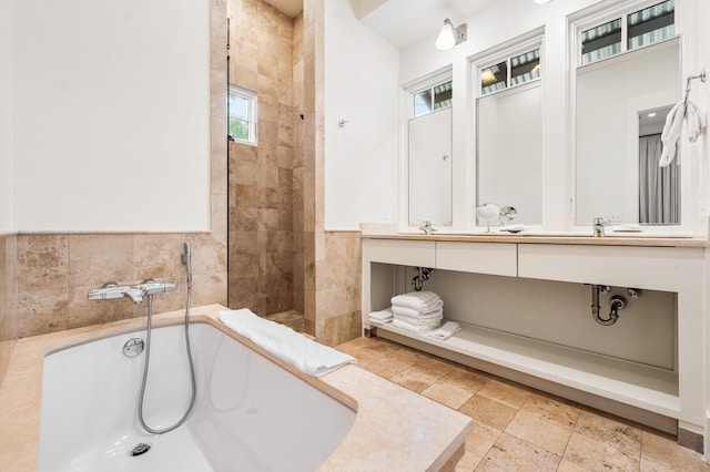 bathroom with shower with separate bathtub, vanity, and tile walls