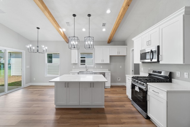 kitchen featuring beam ceiling, a kitchen island, white cabinets, and appliances with stainless steel finishes