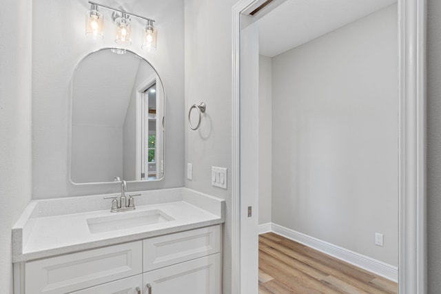 bathroom with wood finished floors, vanity, and baseboards