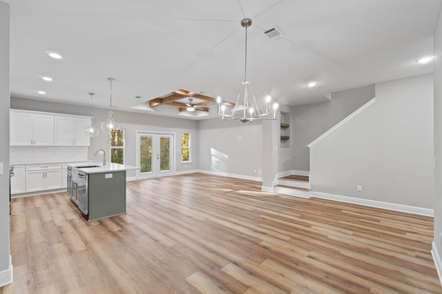 kitchen featuring white cabinets, open floor plan, light countertops, an island with sink, and pendant lighting