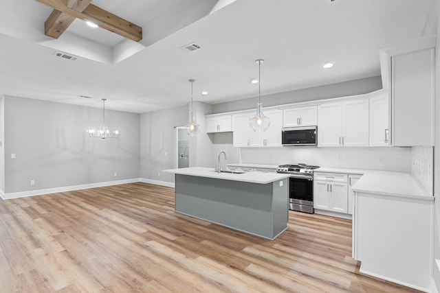 kitchen with appliances with stainless steel finishes, white cabinets, light countertops, and a center island with sink