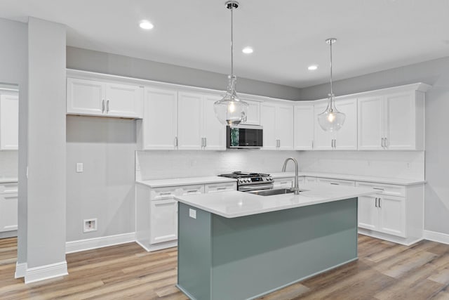 kitchen with white cabinets, light countertops, a sink, and hanging light fixtures