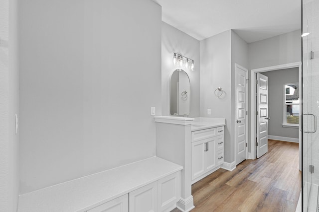 full bath with wood finished floors, a shower stall, vanity, and baseboards