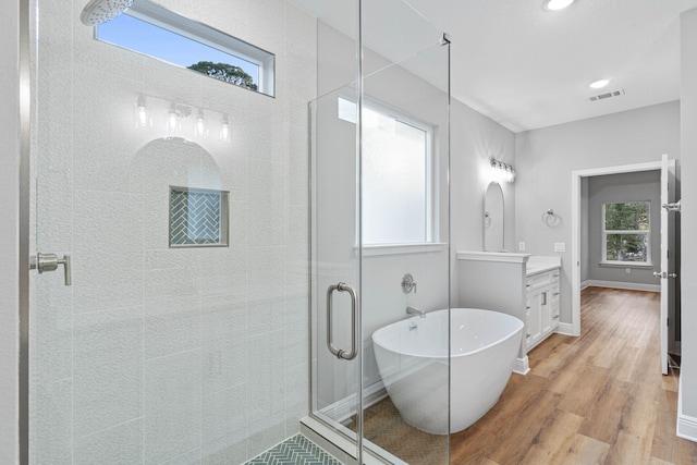 bathroom with a stall shower, baseboards, wood finished floors, a freestanding bath, and vanity