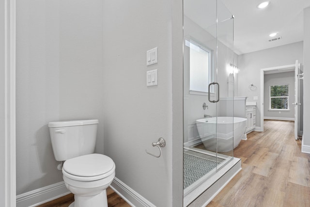 full bathroom with visible vents, toilet, vanity, wood finished floors, and a freestanding tub