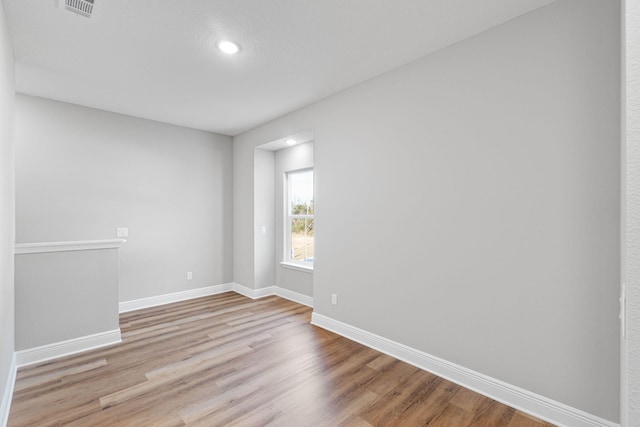 unfurnished room featuring light wood finished floors, visible vents, and baseboards