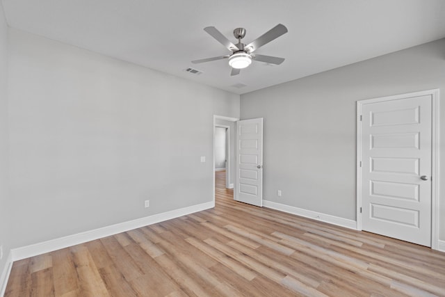 spare room featuring light wood-type flooring, baseboards, visible vents, and a ceiling fan