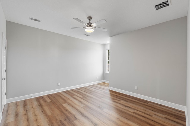 unfurnished room featuring light wood finished floors, a ceiling fan, visible vents, and baseboards