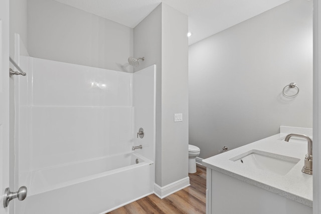 bathroom featuring double vanity, toilet, wood finished floors, shower / washtub combination, and a sink