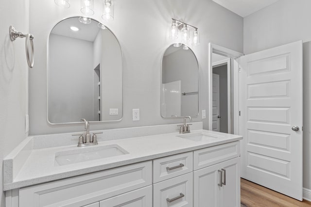 full bath featuring double vanity, a sink, and wood finished floors