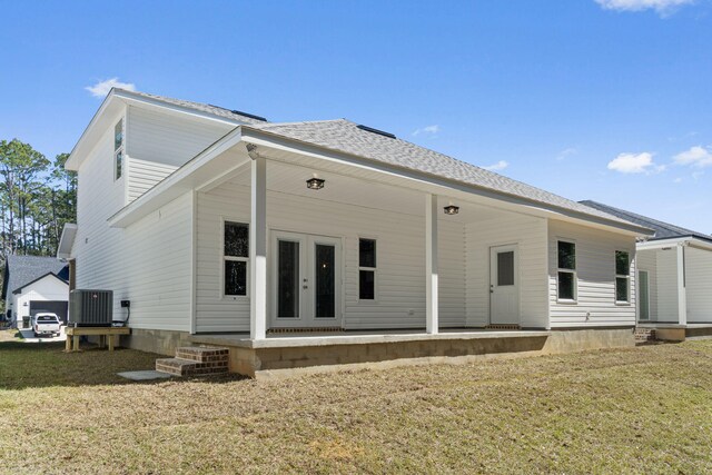 rear view of property with roof with shingles, french doors, a lawn, and central AC unit