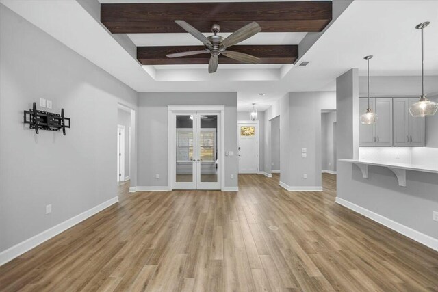 unfurnished living room featuring beam ceiling, light hardwood / wood-style flooring, french doors, and ceiling fan