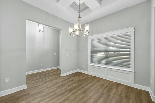 empty room featuring an inviting chandelier and hardwood / wood-style flooring