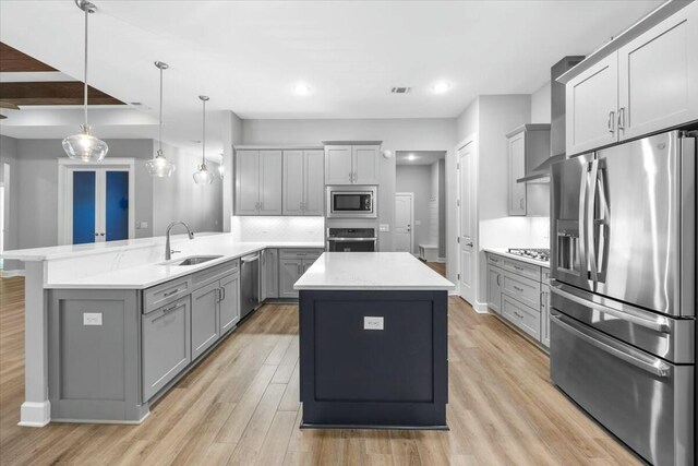 kitchen with pendant lighting, stainless steel appliances, a kitchen island, and gray cabinetry