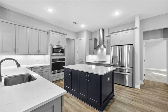 kitchen featuring wall chimney exhaust hood, appliances with stainless steel finishes, sink, and decorative backsplash