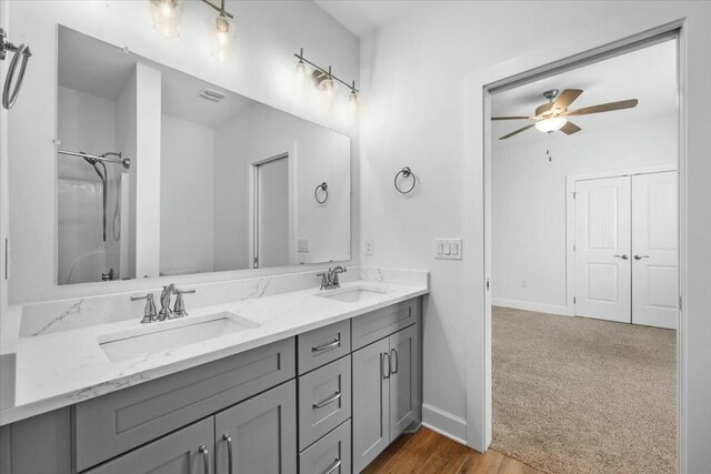 bathroom with walk in shower, ceiling fan, and vanity