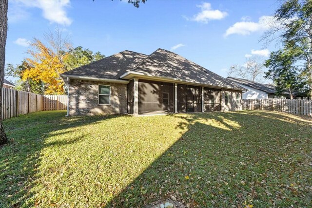 rear view of property with a sunroom and a lawn