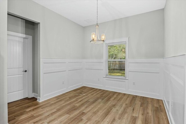 spare room with hardwood / wood-style floors and an inviting chandelier