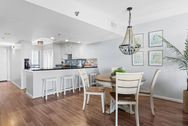 dining area with wood-type flooring and a chandelier