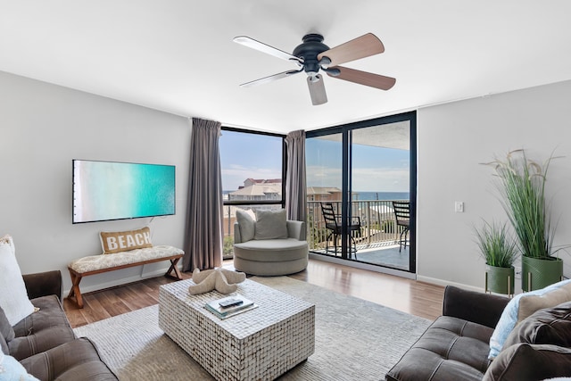 living room with hardwood / wood-style floors, a wall of windows, and ceiling fan