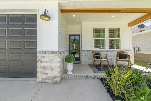 view of exterior entry with covered porch and a garage