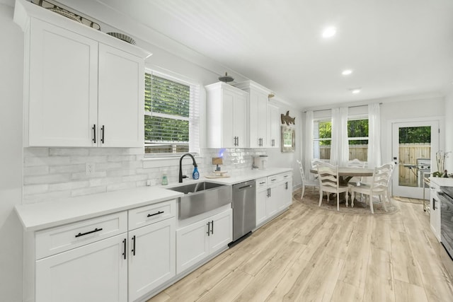 kitchen featuring dishwasher, white cabinets, sink, light wood-type flooring, and tasteful backsplash