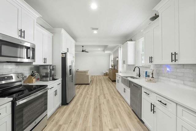 kitchen with light wood-type flooring, tasteful backsplash, stainless steel appliances, ceiling fan, and white cabinetry