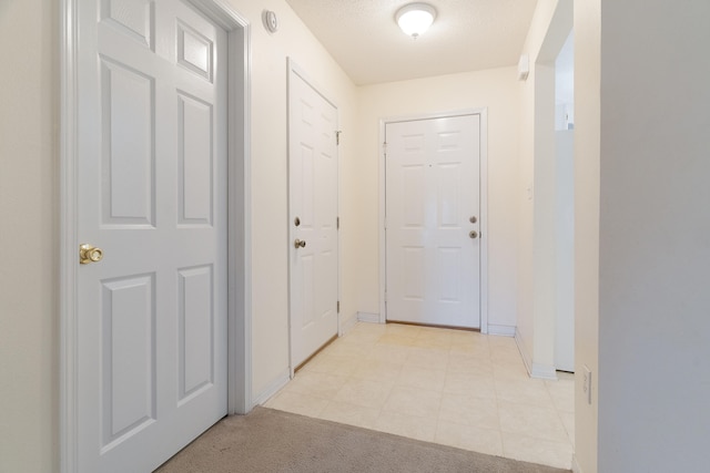 corridor featuring light carpet and a textured ceiling