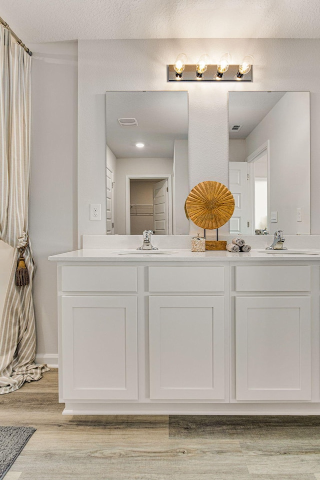 bathroom featuring vanity, wood-type flooring, and a textured ceiling