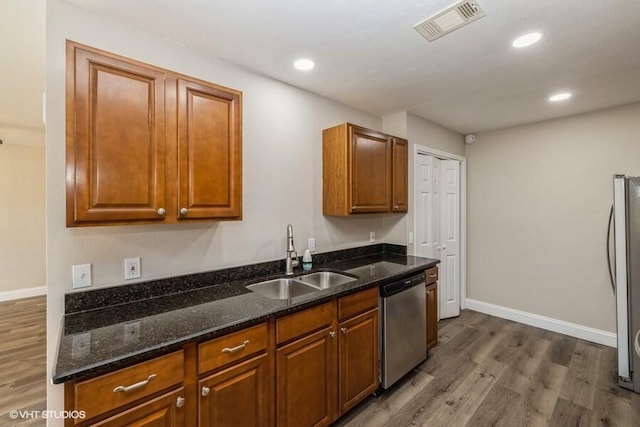 kitchen featuring dark wood-type flooring, sink, appliances with stainless steel finishes, and dark stone counters