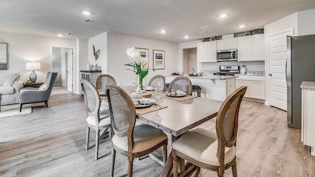 dining area featuring a textured ceiling and light hardwood / wood-style flooring