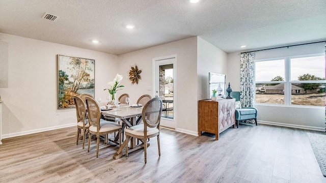 dining space featuring a textured ceiling and light wood-type flooring