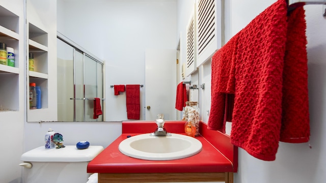 bathroom with vanity, toilet, and a shower with door