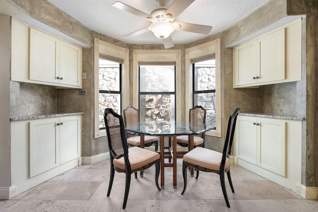 dining area featuring ceiling fan and a textured ceiling