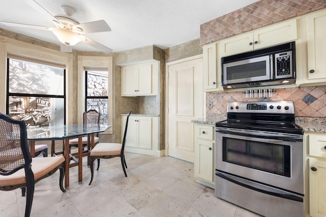 kitchen featuring electric range, ceiling fan, light stone countertops, and cream cabinetry